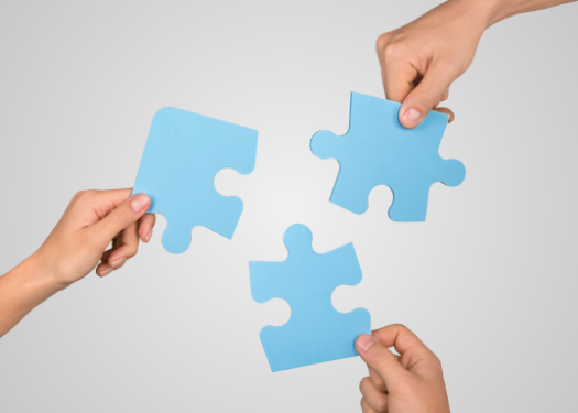 Mehrere Hände versuchen ein Puzzle zusammenzusetzen als Symbol für chaotisches Marketing ohne System